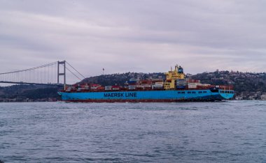 Bebek, İstanbul, Türkiye - 19 Şubat 2021 - İstanbul Boğazı 'nda Fatih Sultan Mehmet Köprüsü' nün arka planında yer alan büyük Maersk yük gemisi