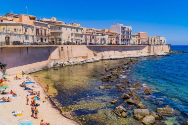 Syracusa, İtalya - 26 Temmuz 2020 - İtalya 'nın Sicilya adasındaki Syracusa şehrinin şehir plajında yüzücüler ve güneşlenenler