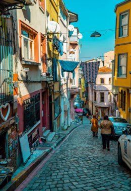 Balat, İstanbul, Türkiye - 23 Şubat 2021 - Balat 'ta ünlü bir sokakta geleneksel ev ve arabalarla turistlerin dikey görüntüsü