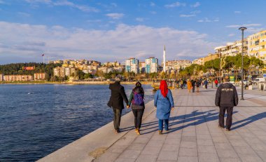 Çanakkale, Türkiye - 1 Mart 2021 - Türkiye 'nin Çanakkale kentindeki Çanakkale Boğazı' nda gün batımında yürüyen insanların sokak fotoğrafı