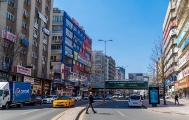 Ankara, Türkiye - 13 Mart 2021 - Kalabalık bir caddede yürüyen bir adamın arabaları ve binaları ile sokak fotoğrafı