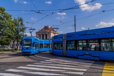 Zagreb, Hırvatistan - 28 Haziran 2020 - Zagreb merkez istasyonunun önündeki köşeyi dönen modern hafif tren ve antik tramvay