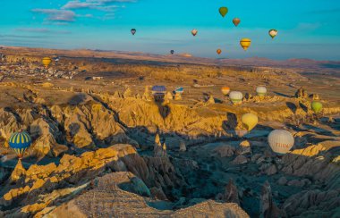 Goreme, Cappadocia, Türkiye - 19 Mart 2021 - Peri bacası, kaya oluşumları ve gün doğumunda Kapadokya 'da dağların üzerinde uçan sıcak hava balonlarının güzel panoramik manzarası