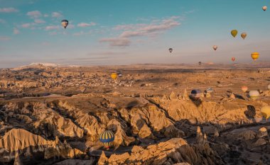 Goreme, Cappadocia, Türkiye - 19 Mart 2021 - Peri bacası, kaya oluşumları ve Kapadokya 'daki dağların üzerinde uçan sıcak hava balonları panoramik hava manzarası