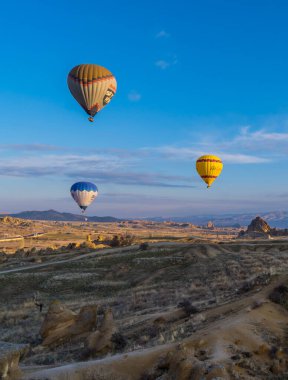 Goreme, Türkiye - 19 Mart 2021 - Cappadocia 'da peri bacaları ve kaya oluşumlarıyla uçan turist sıcak hava balonlarının muhteşem dikey gündoğumu görüntüsü
