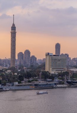 Kahire, Mısır - 25 Mart 2021 - Zamalek 'teki tekneler, Kahire Kulesi ve otellerle Nil Nehri' nin dikey gün batımı görüntüsü