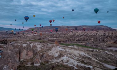 Goreme, Türkiye - 20 Mart 2021 - Türkiye 'nin Kapadokya kentindeki Goreme kasabasında güneş doğarken uçan sıcak hava balonlarının güzel manzarası