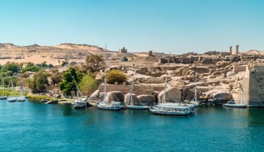 Aswan, Mısır - 2 Nisan 2021 - Nil 'deki botların panoramik görüntüsü ve arka planda Fil Adası' ndaki tapınak