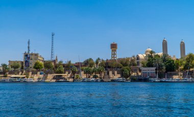 Aswan, Mısır - 2 Nisan 2021 - Nil nehri üzerindeki Aswan şehrinin panoramik manzarası, tekneleri, Aswan Katedrali ve binaları