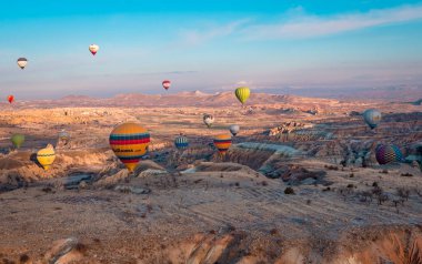 Urgup, Cappadocia, Türkiye - 19 Mart 2021 - Peri bacaları, kaya oluşumları ve Kapadokya 'daki dağların üzerinde uçan sıcak hava balonları panorama hava manzarası