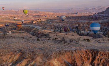 Urgup, Cappadocia, Türkiye - 19 Mart 2021 - Peri bacası, kaya oluşumları ve Kapadokya 'daki dağlar üzerinde uçan sıcak hava balonlarının panoramik görüntüsü