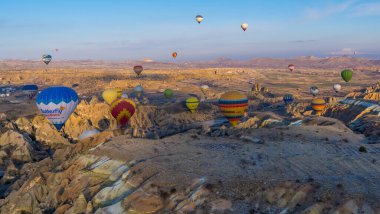 Urgup, Cappadocia, Türkiye - 19 Mart 2021 - Peri bacaları, kaya oluşumları ve sabah Kapadokya 'daki dağların üzerinde uçan sıcak hava balonlarının güzel panoramik manzarası