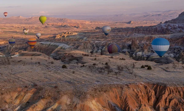 Urgup, Cappadocia, Türkiye - 19 Mart 2021 - Peri bacası, kaya oluşumları ve Kapadokya 'daki dağlar üzerinde uçan sıcak hava balonlarının panoramik görüntüsü