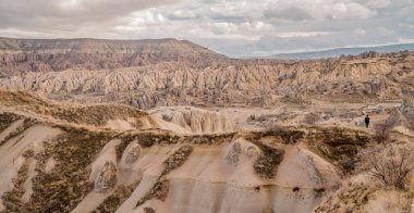 Türkiye 'nin Goreme kenti yakınlarındaki Kapadokya manzaraları panoramik manzaralı kayaların üzerinde duran kimliği belirsiz turist