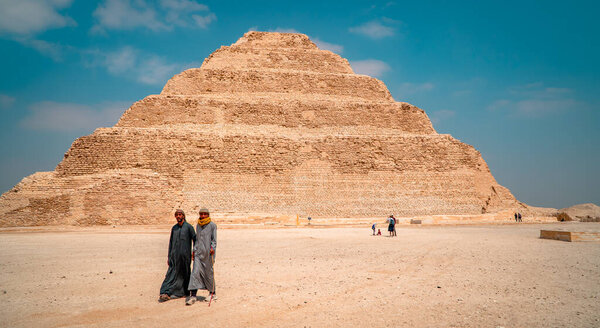Saqqara, Egypt - April 1, 2021 - panoramic view of locally-dressed men at the Pyramid of Djoser, the oldest pyramid in all of Egypt