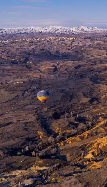 Vertical view of a hot air balloon flying through spectacular landscapes in Cappadocia, Turkey
