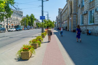 Chisinau, Moldova - 25 Haziran 2021 - Chisinau şehir merkezinde gizli sokak fotoğrafçısı ve çiçekli bir kadın