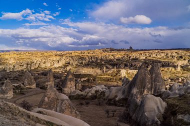 Goreme, Cappadocia, Türkiye 'deki eşsiz kaya oluşumları ve tipik peri bacalarının panoramik günbatımı görüntüsü