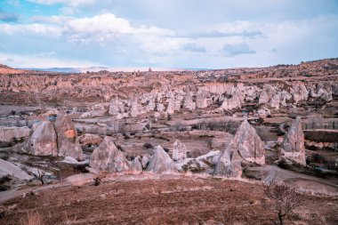 Göreme, Kapadokya, Türkiye 'deki eşsiz kaya oluşumları ve tipik peri bacalarının muhteşem panoramik günbatımı görüntüsü