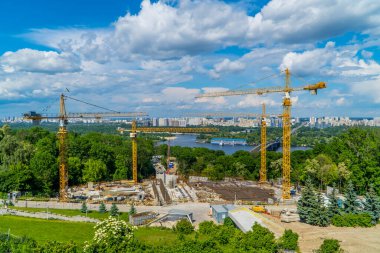 Kyiv, Ukrayna - 7 Haziran 2021 - Kiev 'deki Dinyeper Nehri' nin diğer tarafındaki bir inşaat alanının panoramik manzarası ve komünist yerleşim blokları