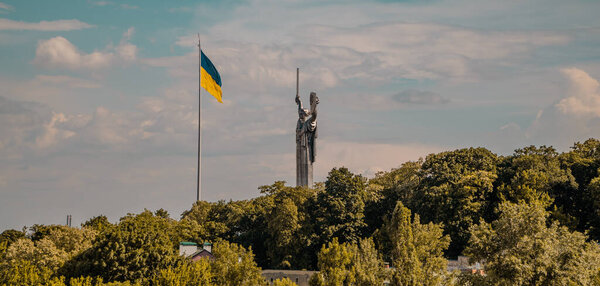 Kyiv, Ukraine - June 7, 2021 - panoramic sunset view of the Motherland Monument and Ukrainian flag