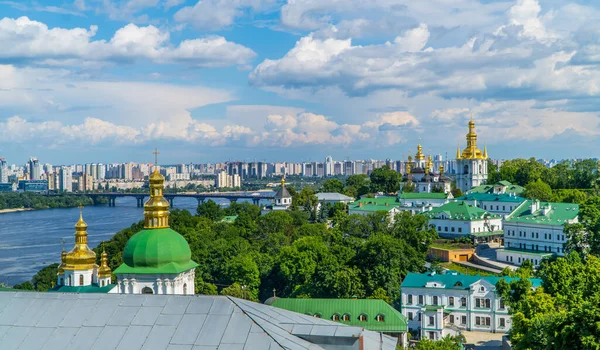 Kyiv, Ukrayna - 7 Haziran 2021 - Pechersk Lavra altın kaplama Ortodoks kiliseleri ve, Dinyeper nehri ve arka plandaki sosyalist yerleşim blokları panoramik görünümü