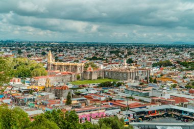 Cholula, Puebla, Meksika - 29 Ağustos 2021 - renkli evler ve Cholula Piramidi 'nden San Gabriel Konvansiyonu bulutlu bir günde