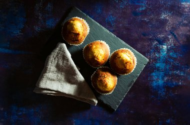 Paslı, mavi bir arka planda, çarşaf bezli, tahta tabakta çörekler. Koyu Yemek