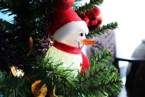 Suni Noel ağacında parlayan hafif kardan adam bebeği.