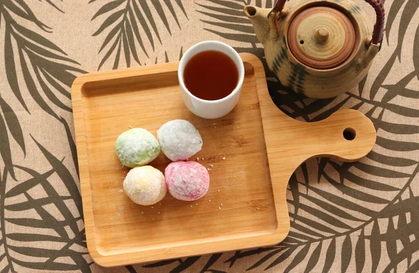Daifuku Mochi ve yeşil çay, tahta tepsiye koyun. Yakınlarda bir çaydanlık var. Üst görüntü fotoğrafı.
