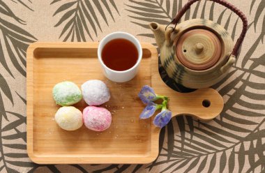 Daifuku Mochi ve yeşil çay, tahta tepsiye koyun. Yakınlarda bir çaydanlık var. Üst görüntü fotoğrafı.