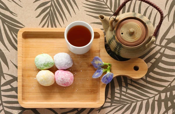 Daifuku Mochi ve yeşil çay, tahta tepsiye koyun. Yakınlarda bir çaydanlık var. Üst görüntü fotoğrafı.