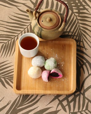 Daifuku Mochi doldurulmuş kırmızı fasulye ezmesi ve ahşap tepsi ve yeşil çay. Yakınlarda bir çaydanlık var. Geleneksel bir Japon şekerlemesi..