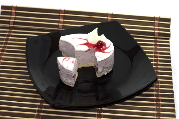O fez uma incisão bolo branco, em uma chapa preta, em um tapete — Fotografia de Stock
