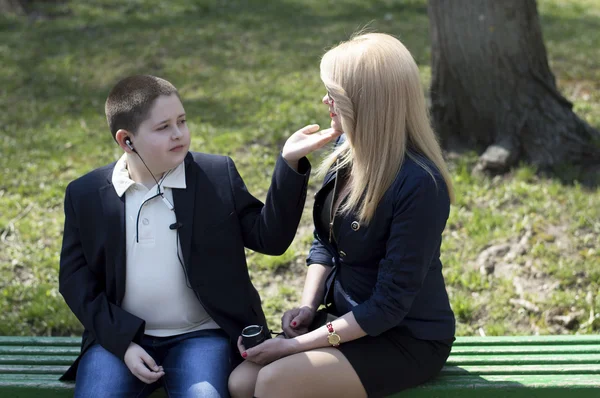 Görüşmeler için bir bankta oturan çocuk, genç anne