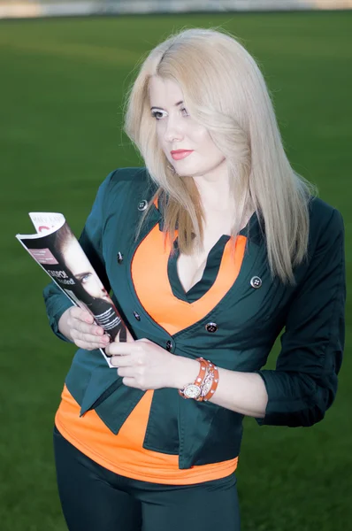 Das schöne Mädchen mit dem Frauenmagazin im Stadion — Stockfoto