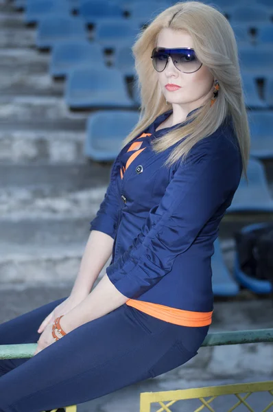 Красивая девушка сидит на барьере на стадионе — стоковое фото