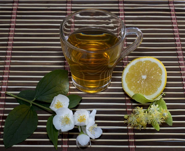 Bicchiere di tè da un tiglio con un limone su un tappetino — Foto Stock