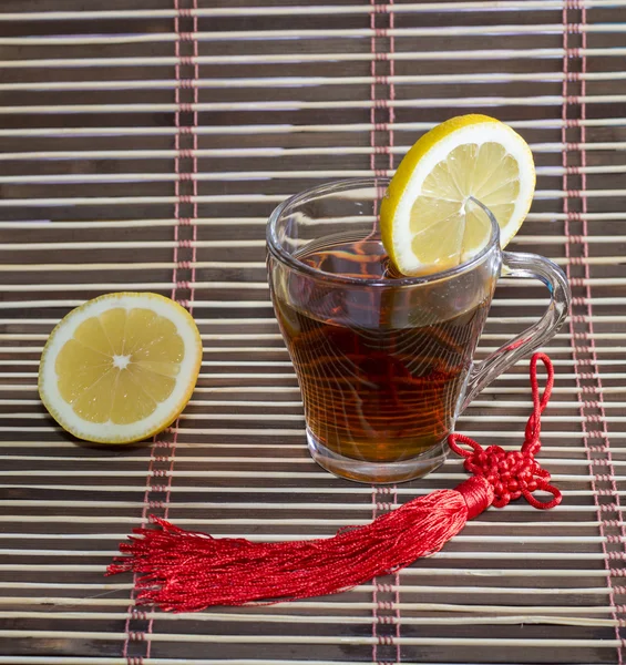 Glass of tea and nearby lemon, on a rug — Stock Photo, Image