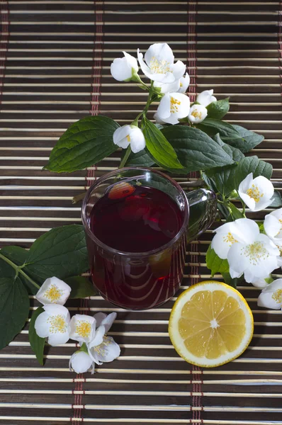 Glass of red tea, nearby lemon and flower — Stock Photo, Image