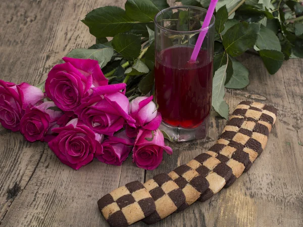 Стакан сока с букетом роз и печенья — стоковое фото