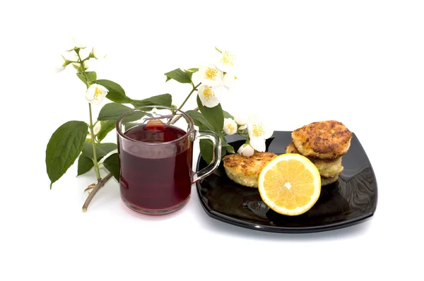 Thé, citron et gâteaux au fromage sur une assiette les boissons décorées d'une branche de fleurs — Photo