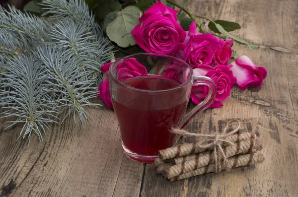 Roses, a fir-tree branch and a mug of juice at center — Stock Photo, Image