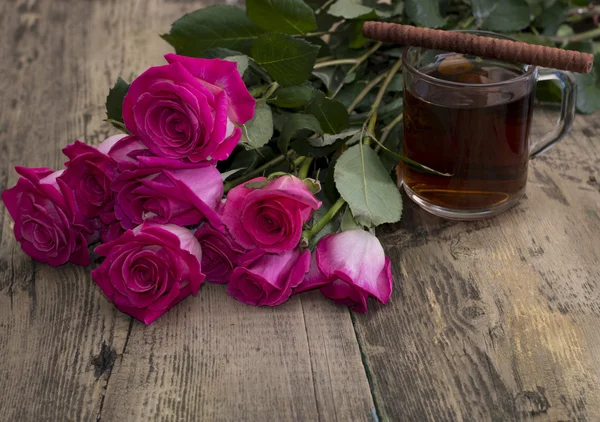 Glass of strong tea, cookies and bouquet of scarlet roses — Stock Photo, Image