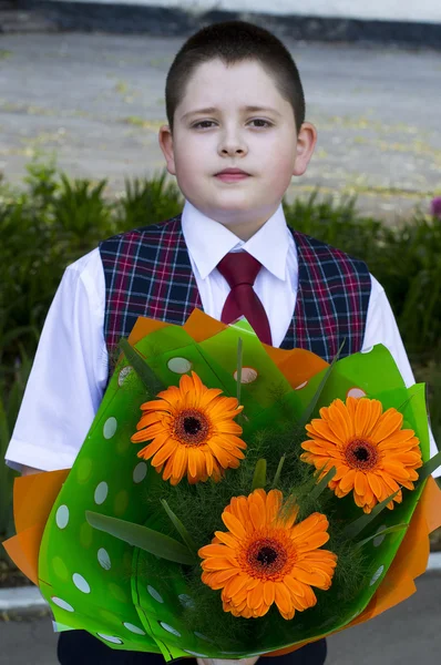 The beautiful school student with a bouquet of bright orange flowers — Stock Photo, Image