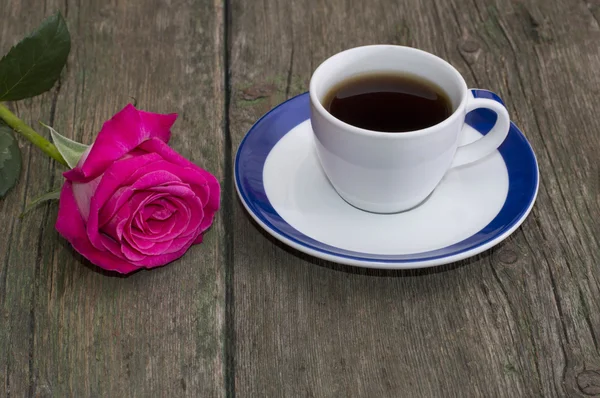 Taza de café y rosa roja solitaria en una mesa —  Fotos de Stock