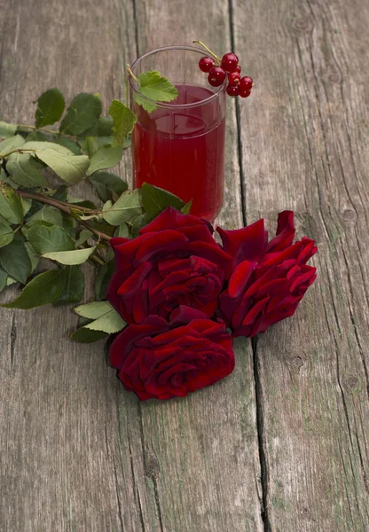 Склянка соку, смородина на склянці і букет червоних троянд — стокове фото