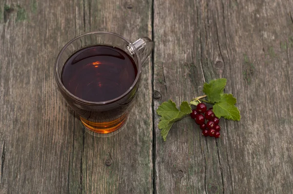 Transparent cup of tea and branch of red currant on a shabby tab — Stock Photo, Image