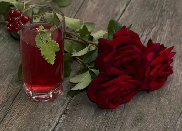 Букет з червоних троянд і скла з червоним напоєм — стокове фото