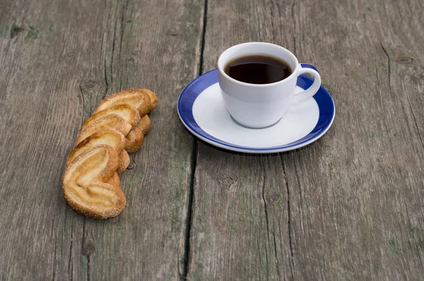 Φλιτζάνι καφέ σε ένα πιατάκι με ένα μπλε περίγραμμα και τα cookies σε μια ro — Φωτογραφία Αρχείου